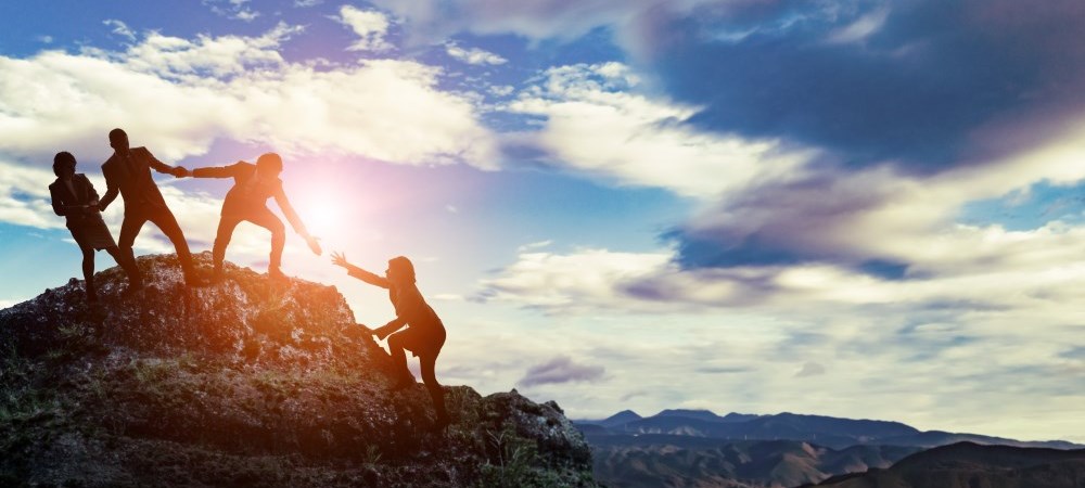 People Helping each other climb a mountain